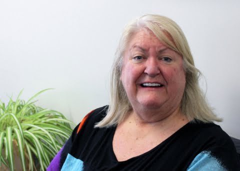 Woman in a caring role smiles at the camera in an office area