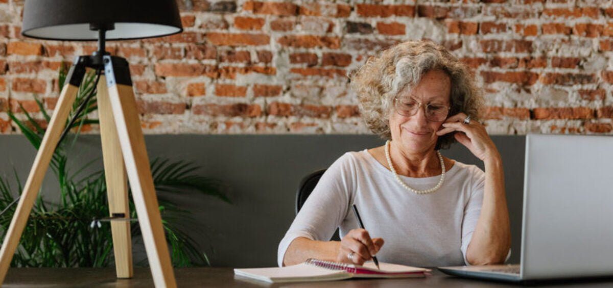 Woman sitting at a desk writing on the phone