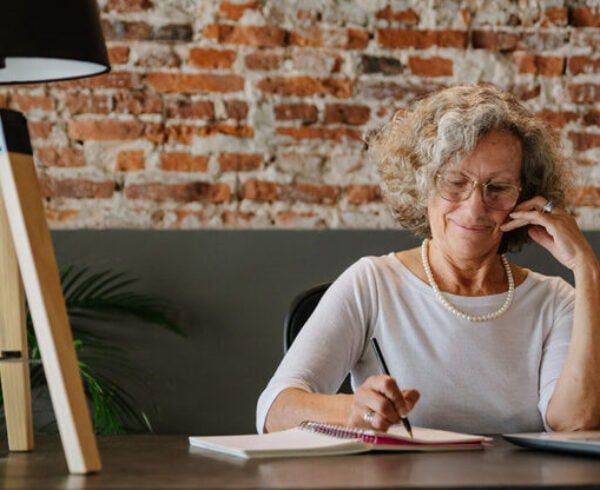 Woman sitting at a desk writing on the phone